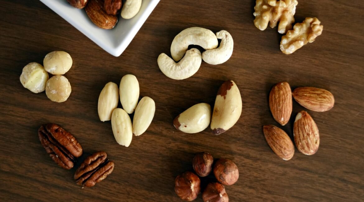 "Diversos tipos de frutos secos sobre uma mesa de madeira, incluindo nozes, amêndoas e castanhas-do-pará."